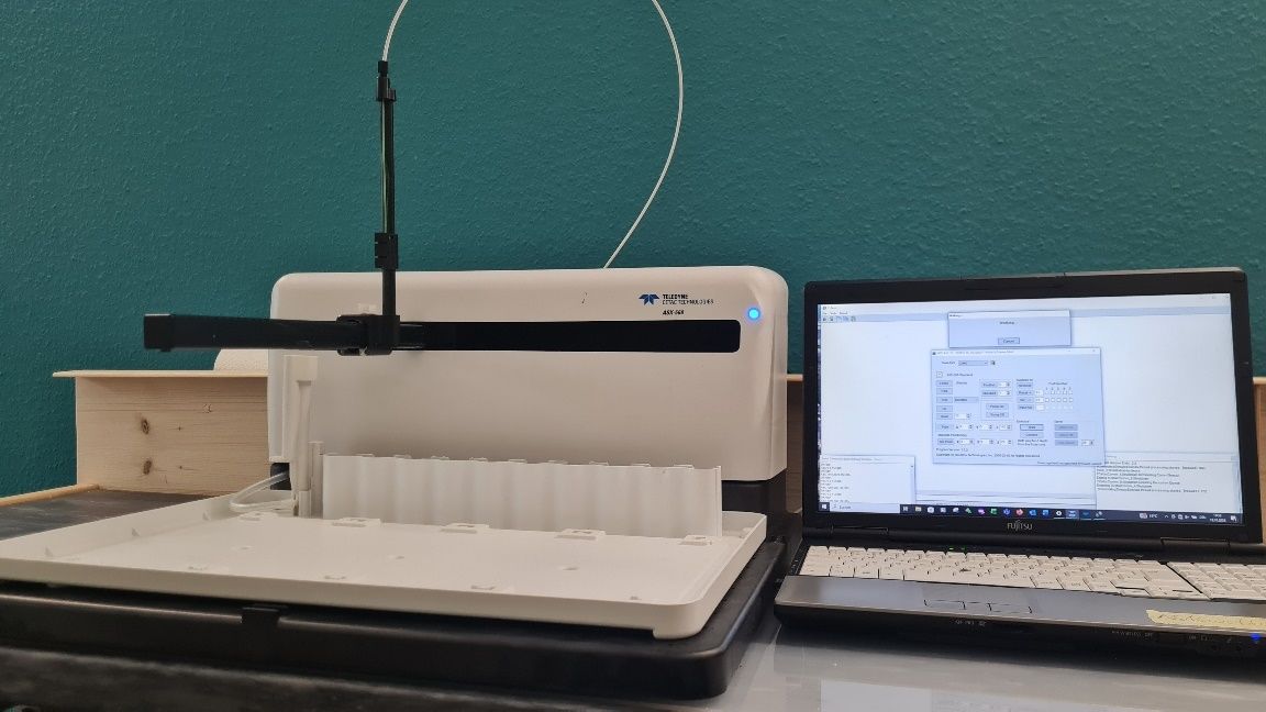 Autosampler im Testbetrieb am Werkstattplatz, daneben ein Laptop mit Steuersoftware
